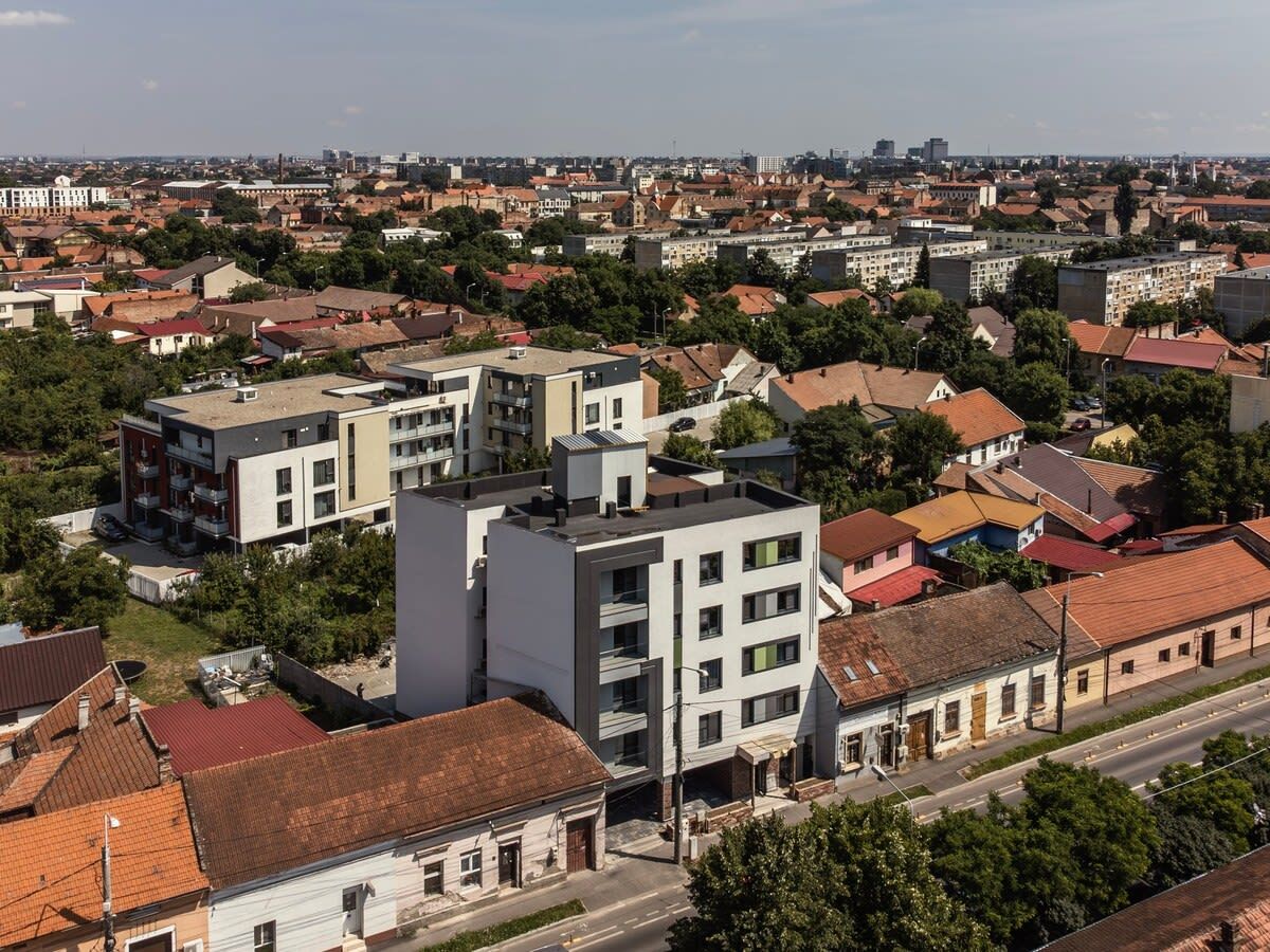 Zona residencial con edificios modernos y tradicionales, incluyendo un edificio de apartamentos blanco destacado con balcones.