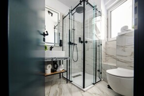 A modern bathroom with a glass-enclosed shower, a white toilet, and a marble-tiled floor. - GBU Home - Azure Room Executive (Timișoara)