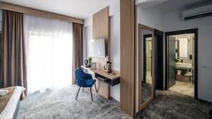 Een moderne hotelkamer met een bureau, stoel en een grote spiegel.
