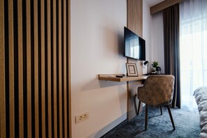 A hotel room with a bed, a desk with a flat-screen TV, a chair, and a window with curtains. - GBU Home - Olive Tween Room 206 (Timișoara)