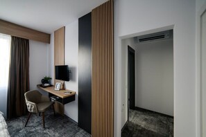A modern hotel room with a desk, chair, TV, and a large wooden panel on the wall. - GBU Home - Olive Tween Room 206 (Timișoara)