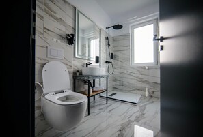 A modern bathroom with a marble floor, a white toilet, a sink with a mirror, and a shower area. - GBU Home - Olive Tween Room 206 (Timișoara)