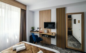 A hotel room with a bed, a desk with a TV, a mirror, and a wardrobe. - GBU Home Azure Room 301 (Timișoara)