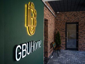 A building entrance with a sign reading 'GBUHome' and a brick wall.