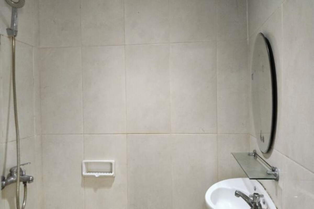 Un baño con ducha, lavamanos y espejo.