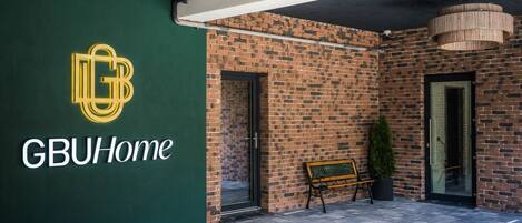 A GBUHome entrance with a brick wall, a bench, and a potted plant.