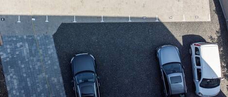 An aerial view of a parking lot with three cars and a white van.