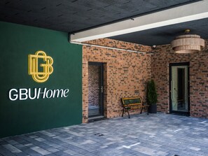 Entrada da GBUHome com uma parede de tijolos, um banco e uma planta em vaso.