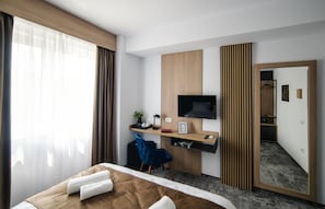 Une chambre d’hôtel comprenant un lit, un bureau avec un ordinateur, une télévision, un miroir et une armoire.