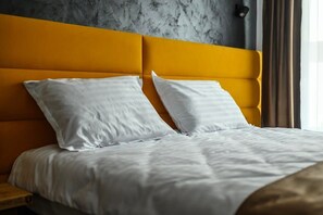 A bed with white bedding and a yellow headboard in a room with a textured gray wall. - GBU Home Timisoara Honey 402 (Timișoara)