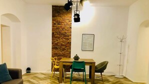 Una sala de estar con piso de espiga, una pared de acento de ladrillo, una mesa de comedor de madera con sillas, un sofá y una lámpara de pie.