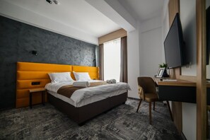 Una camera d'albergo moderna con un letto grande, una scrivania e una televisione.