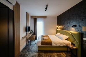 A modern hotel room with a bed, a desk, and a chair.