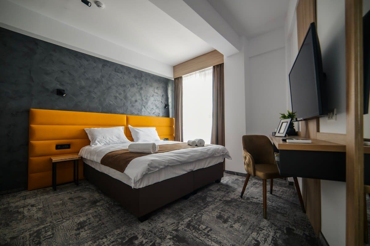 A modern hotel room with a large bed, a desk, and a television.