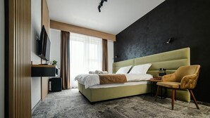 A modern hotel room with a large bed, a television, a small table, and a chair. - GBU Home Timisoara Olive 407 (Timișoara)