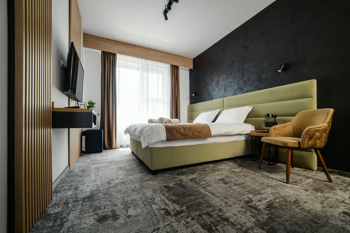 A modern hotel room with a large bed, a television, a small table, and a chair.