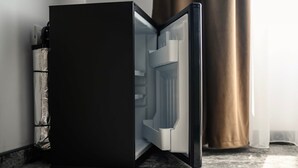 A modern, black-framed refrigerator with a metallic handle, positioned against a wall with a metallic curtain. - GBU Home Timisoara Olive 407 (Timișoara)