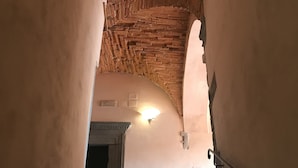 A staircase with a brick archway leading to a room with a light fixture and a door. - I Borghi della Maddalena (Borgo a Mozzano)