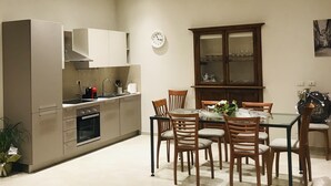 A modern kitchen with built-in appliances, a dining area with a glass table, and a wooden cabinet. - I Borghi della Maddalena (Borgo a Mozzano)