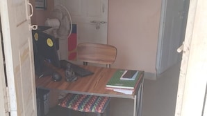 A classroom with a wooden desk, a chair, a poster on the wall, and a door. - Jungle by sturmfrei Gokarna (Kumta)