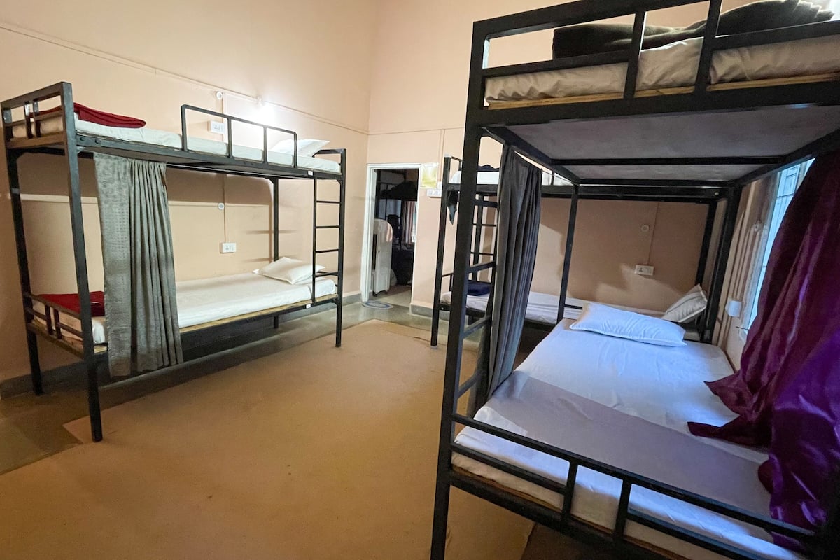 Ein Schlafsaalzimmer mit Etagenbetten, einer Tür und einem Fenster.