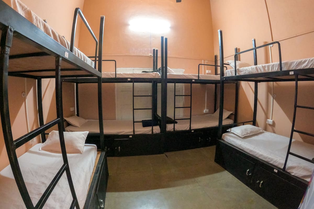Ein Schlafsaalzimmer mit Etagenbetten, einem Deckenventilator und einem Fenster.