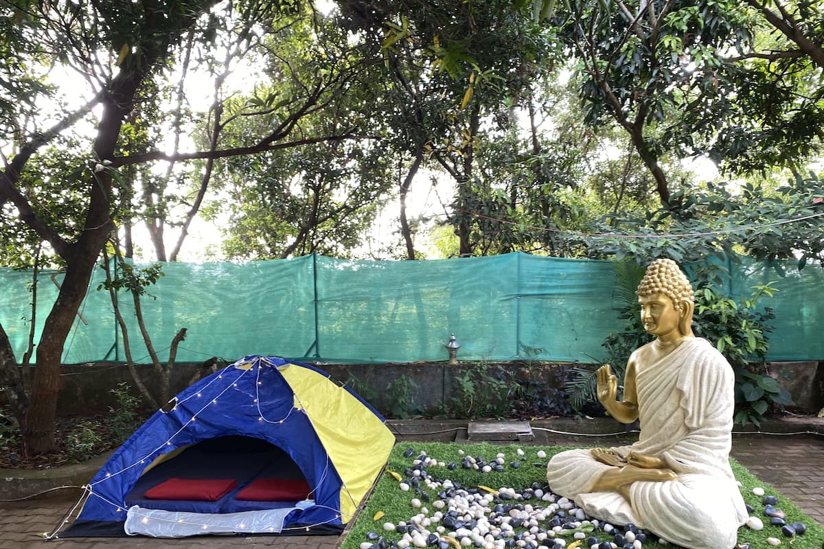 Eine Buddha-Statue auf einer Plattform mit einem Zelt und Kieselsteinen.