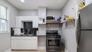 Una cocina compacta con armarios blancos, un microondas, una estufa y un refrigerador.
