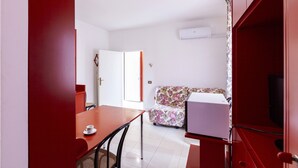 A room with a dining table, a sofa, and a TV.