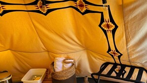Ein gemütlicher Zeltenbereich mit gepolsterten Sitzgelegenheiten, einem kleinen Tisch mit einer Aufbewahrungsbox und einem gewebten Korb.