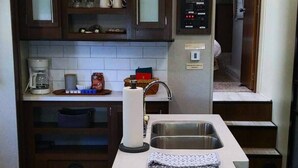 A modern kitchen with dark wooden cabinets, a stainless steel sink, and a coffee maker. - Reconnect with nature at this unforgettable escape (O'Brien)