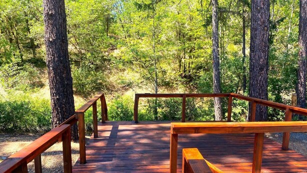 A wooden deck with benches and railings, surrounded by trees. - Reconnect with nature at this unforgettable escape (O'Brien)