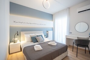 Un dormitorio moderno con una cama, mesitas de noche, un escritorio y una silla.