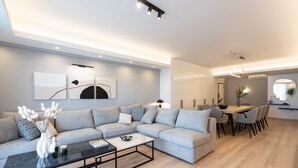 Un salon moderne comprenant un canapé d’angle, une table basse et un coin repas avec une table et des chaises.