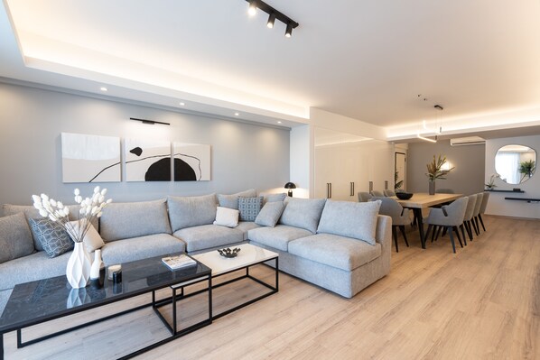 Una sala de estar moderna con un sofá seccional, una mesa de centro y un comedor con una mesa y sillas.
