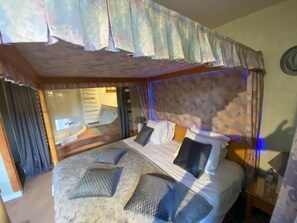 Een slaapkamer met een groot bed, een hoofdbord met een patroon en een nachtkastje met een lamp.
