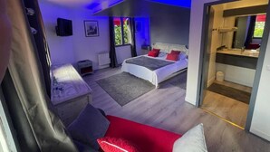 Une chambre moderne avec un lit, un petit coin salon et une vue sur l’extérieur.