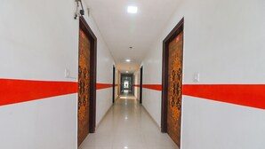 A long, narrow hallway with white walls and red stripes, leading to a door at the end. - Fabexpress Abode Inn (New Delhi)