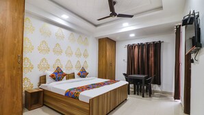 A bedroom with a wooden bed, a desk, and a ceiling fan. - Fabexpress Abode Inn (New Delhi)