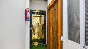 Um corredor estreito com uma porta de madeira e um extintor fixado na parede.