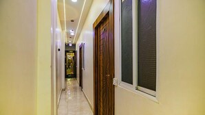 Um corredor com uma porta de madeira, uma janela e uma porta com padrão decorativo.