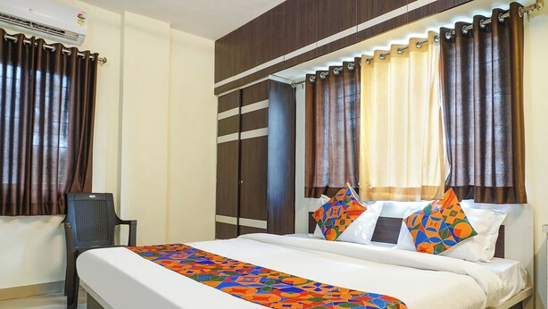 Una habitación de hotel con cama, cortinas, aire acondicionado y una silla.