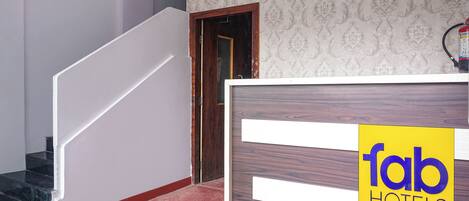 A hotel reception desk with a sign reading 'fab hotels' and a staircase leading to an upper floor.
