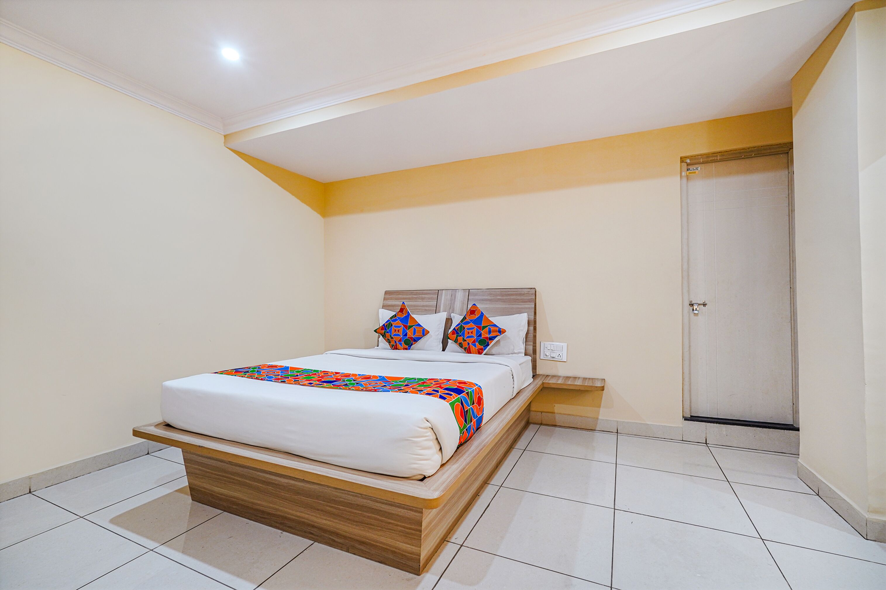 A bedroom with a bed, a wooden headboard, a bedside table, and a door.