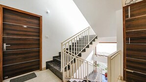 Un interior moderno con una escalera, puertas de madera y vistas al exterior.
