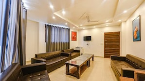 Un salón amplio con sofás de cuero, una mesa de centro y un televisor de pantalla plana montado en la pared.