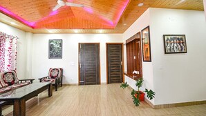 Una habitación amplia con techo de madera, una mesa de comedor con sillas y dos puertas.