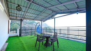 Un espacio al aire libre cubierto con una mesa, sillas y una hamaca, con vistas al paisaje.