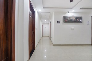 A hallway with wooden doors, a tiled floor, and a framed picture on the wall. - Fabhotel Akash Inn (Agra)