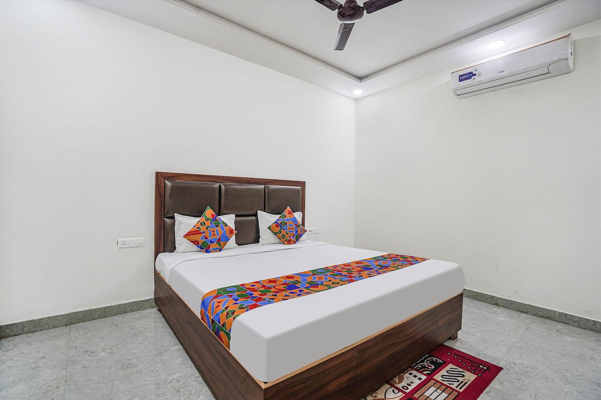 A bedroom with a wooden bed, white walls, and a ceiling fan.
